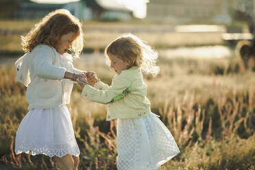 Playful girls holding hands and having fun on sunny day - ANAF00557