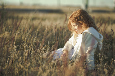 Mädchen sitzt mit geschlossenen Augen im Gras - ANAF00558