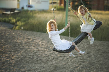 Mädchen schwingen zusammen auf einer Schaukel im Park - ANAF00567