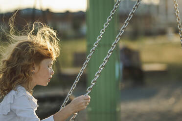 Girl swinging on swing at park - ANAF00568