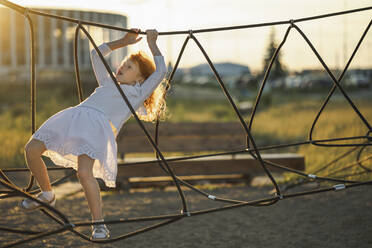 Mädchen klettert Strickleiter im Park - ANAF00572