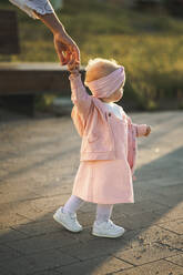 Girl holding hand of mother on footpath - ANAF00574