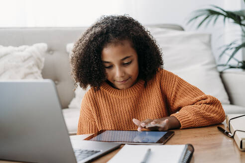 Girl using tablet PC in living room at home - EBBF07153