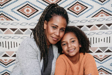 Smiling mature woman with daughter in front of patterned backdrop - EBBF07189