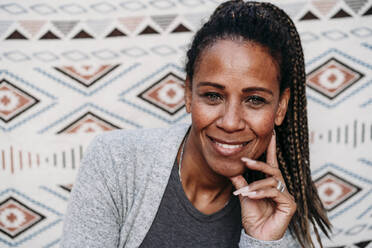 Smiling mature woman in front of patterned backdrop - EBBF07192