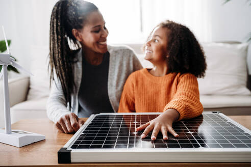 Happy mother and daughter with solar panel at home - EBBF07218