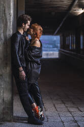 Romantic boyfriend with girlfriend leaning on wall at underpass - IFRF01858