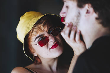 Young girlfriend wearing sunglasses holding boyfriend's face - IFRF01891