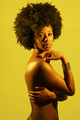 Selbstbewusste nackte Frau mit Afrofrisur vor gelbem Hintergrund - JSMF02510
