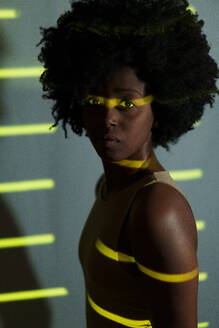 Frau mit Afro-Frisur stehend mit gelben Streifen auf ihr - JSMF02514