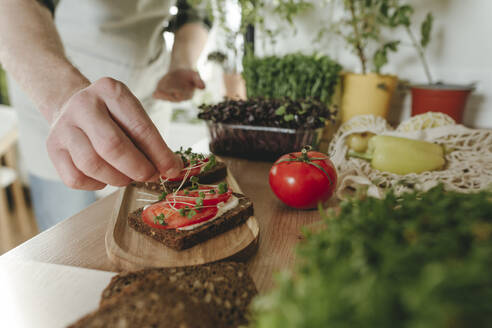Mann macht Sandwich mit selbst angebautem Mikrogrün in der Küche zu Hause - YTF00323
