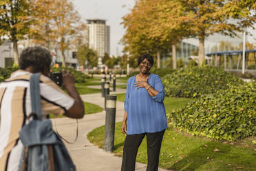 Mann fotografiert Frau durch eine im Park stehende Kamera - JCCMF08175