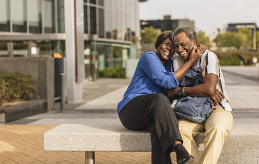 Happy senior couple spending leisure time with each other sitting on bench - JCCMF08187