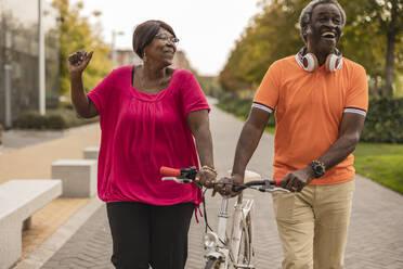 Glückliches älteres Paar, das zusammen im Park Fahrrad fährt - JCCMF08207