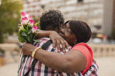 Frau mit Blumenstrauß umarmt Mann - JCCMF08257