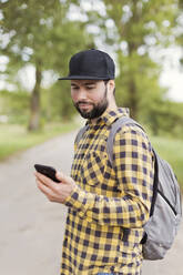 Mann schaut auf der Straße auf sein Mobiltelefon - ONAF00274