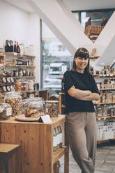 Smiling entrepreneur standing with arms crossed in convenience store - NDEF00144