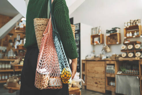 Customer carrying groceries in mesh bag at shop - NDEF00195