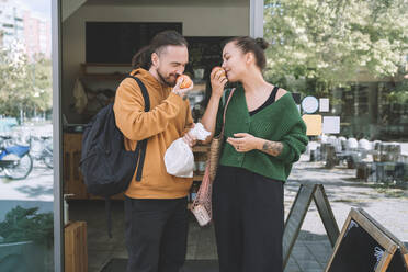 Couple smelling apples standing outside zero waste shop - NDEF00209