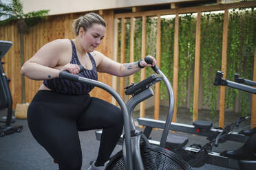 Übergewichtige Frau beim Training auf dem Crosstrainer im Fitnessstudio - SNF01606