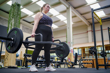 Engagierte junge Frau beim Krafttraining im Fitnessstudio - SNF01616