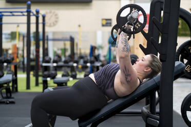 Junge Frau beim Brusttraining im Fitnessstudio - SNF01617