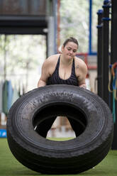 Junge Frau beim Training mit Reifen im Fitnessstudio - SNF01622