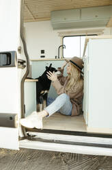 Young woman playing with dog inside motor home - RCPF01507