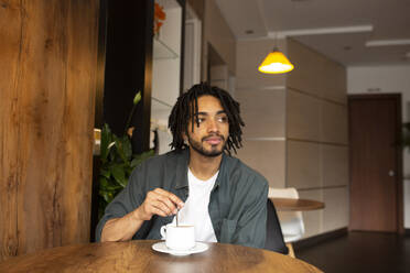 Contemplative man with tea on table at home - DSIF00617