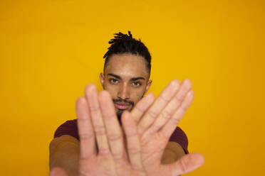 Young man gesturing against yellow background - DSIF00628