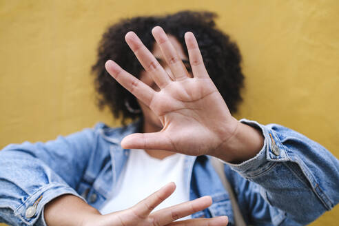 Woman showing stop gesture in front of wall - ASGF03110