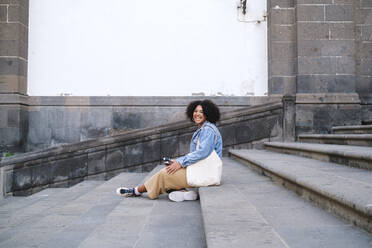 Glückliche junge Frau auf einer Treppe sitzend - ASGF03120