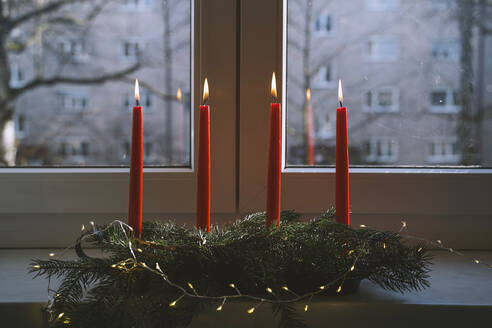 Brennende rote Kerzen auf dem Adventskranz vor dem Fenster zu Hause - NDEF00214