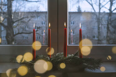 Flaming red candles on table at home in advent - NDEF00215