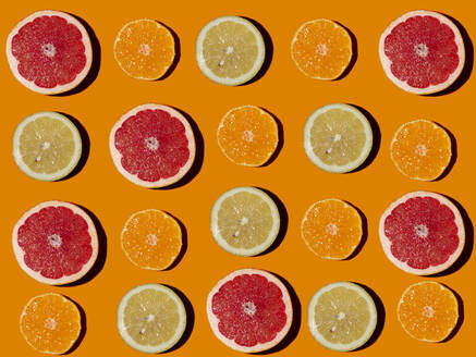 Muster aus halbierten Zitronen, Grapefruits und Mandarinen, flach auf orangefarbenem Hintergrund - GIOF15665