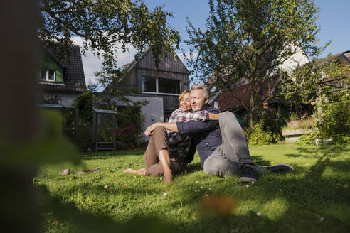 Reife Frau umarmt Mann sitzt auf Gras im Hinterhof - JOSEF15007