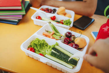 Fresh fruit and vegetable in lunch box on table - MDOF00263