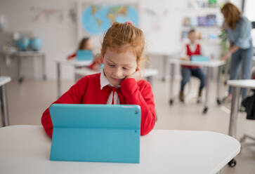 A bored schoolgirl using digital tablet during lesson in classroom at primary school. - HPIF00019