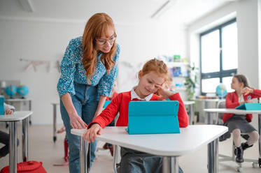 Eine Schülerin benutzt ein Tablet mit Hilfe eines Lehrers während des Unterrichts in der Schule. - HPIF00020