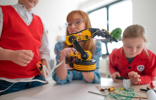 Eine Gruppe von Kindern mit einem jungen Lehrer für Naturwissenschaften programmiert elektrische Spielzeuge und Roboter im Robotik-Klassenzimmer - HPIF00036