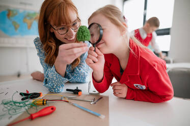 Ein kleiner Schüler mit Down-Syndrom programmiert zusammen mit einem Lehrer elektrische Spielzeuge und Roboter im Robotik-Klassenzimmer - HPIF00037