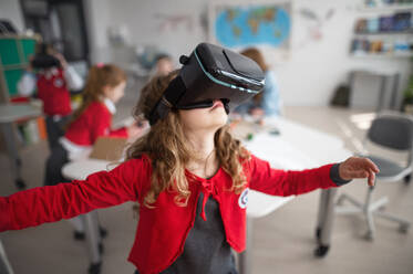 A happy schoolgirl wearing virtual reality goggles at school in computer science class - HPIF00038