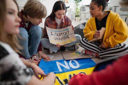 Jugendliche Schüler sitzen im Kreis in einem Klassenzimmer mit Plakaten zur Unterstützung der Ukraine, kein Kriegskonzept. - HPIF00066