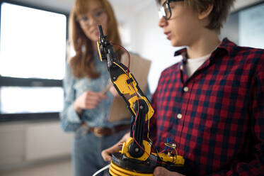 Ein College-Student präsentiert einem jungen Wissenschaftslehrer im Robotik-Klassenzimmer der Schule sein gebautes Roboterspielzeug. - HPIF00088