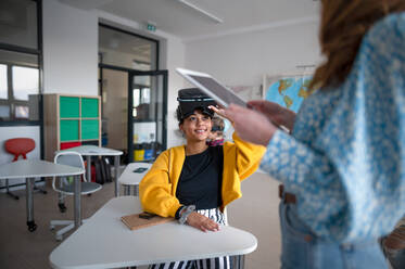 Junger Gymnasiallehrer unterrichtet Schüler mit VR-Brillen in einem Klassenzimmer - HPIF00096
