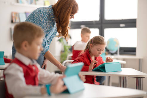 Eine Schülerin mit Down-Syndrom benutzt ein digitales Tablet während einer Unterrichtsstunde in der Grundschule. Integrationskonzept. - HPIF00122
