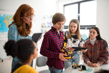 Ein Student präsentiert einem jungen Wissenschaftslehrer und seinen Mitschülern im Robotik-Klassenzimmer der Schule sein selbst gebautes Roboterspielzeug. - HPIF00146