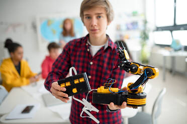 Ein Student hält seinen selbstgebauten Roboter in einem Robotik-Klassenzimmer in der Schule. - HPIF00150