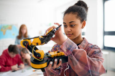 A college student holding her robotic toy at robotics classroom at school. - HPIF00152