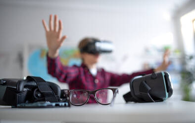 A happy student wearing virtual reality goggles at school in computer science class, close-up at glasses. - HPIF00174